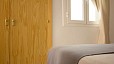 Seville Apartment - Bedroom with a large built-in wardrobe and a window facing an interior patio.