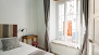 Séville Appartement - Bedroom with a small table and chair. A double glazed window faces Rodrigo de Triana street.